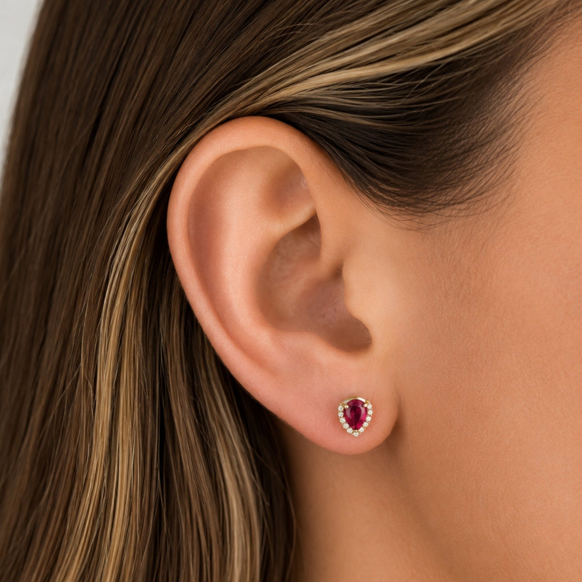 Pear Ruby and Diamond Halo Stud Earrings in 18K Yellow Gold, on ear | JJ Jewelry Miami