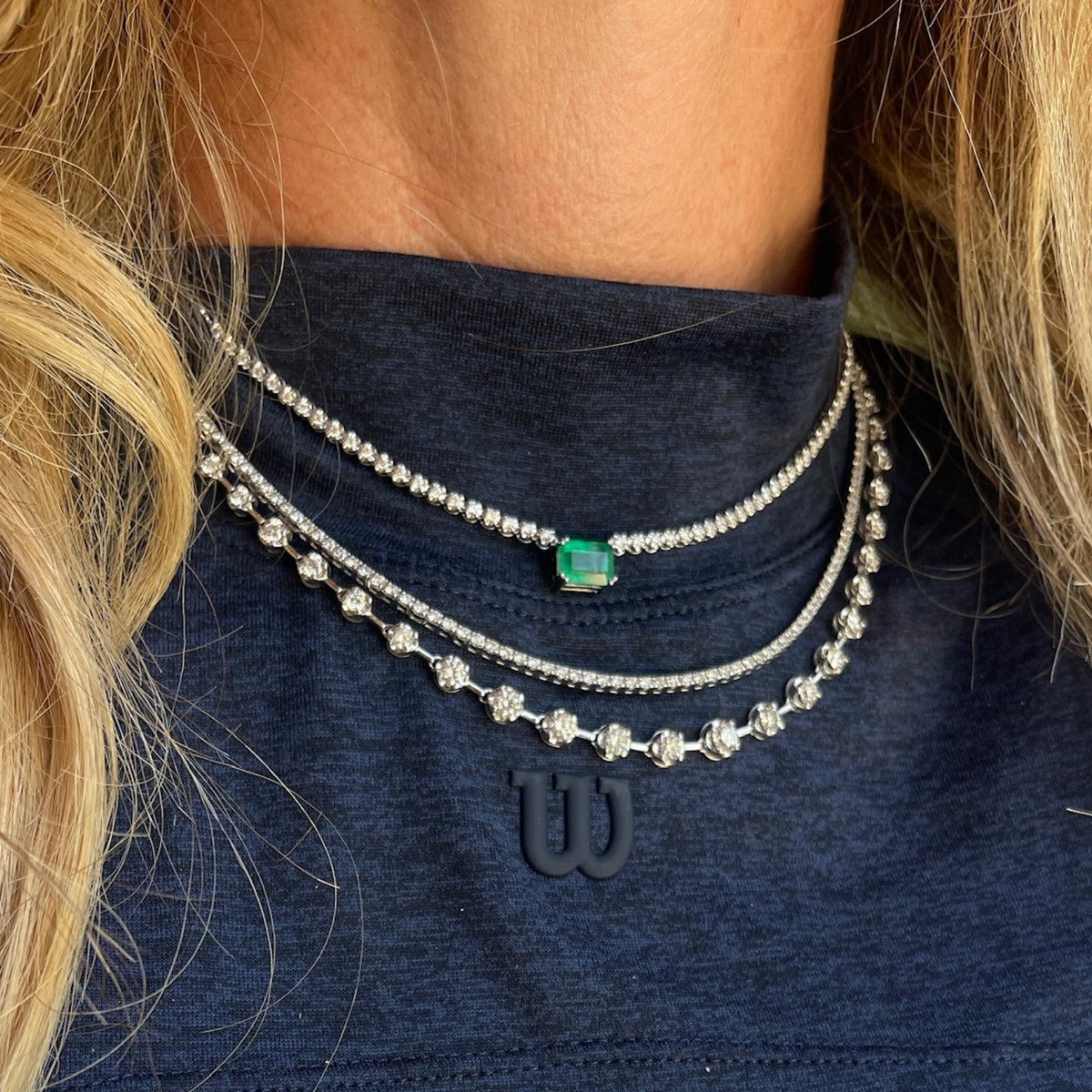 Layered diamond and emerald tennis necklaces in 18K gold worn on model | JJ Jewelry Miami